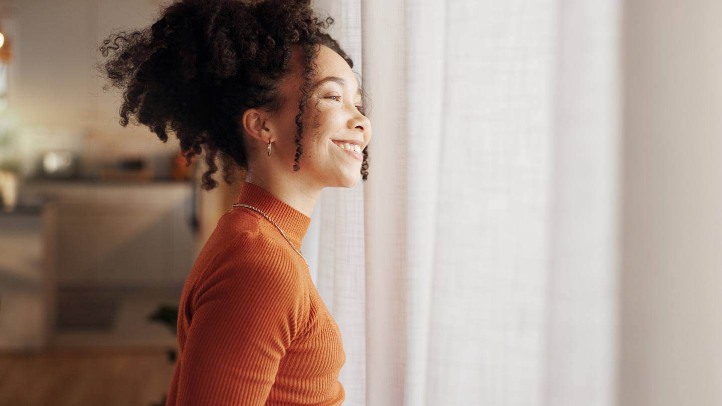 A woman smiling and relaxed at home following bipolar disorder treatment in New Jersey.