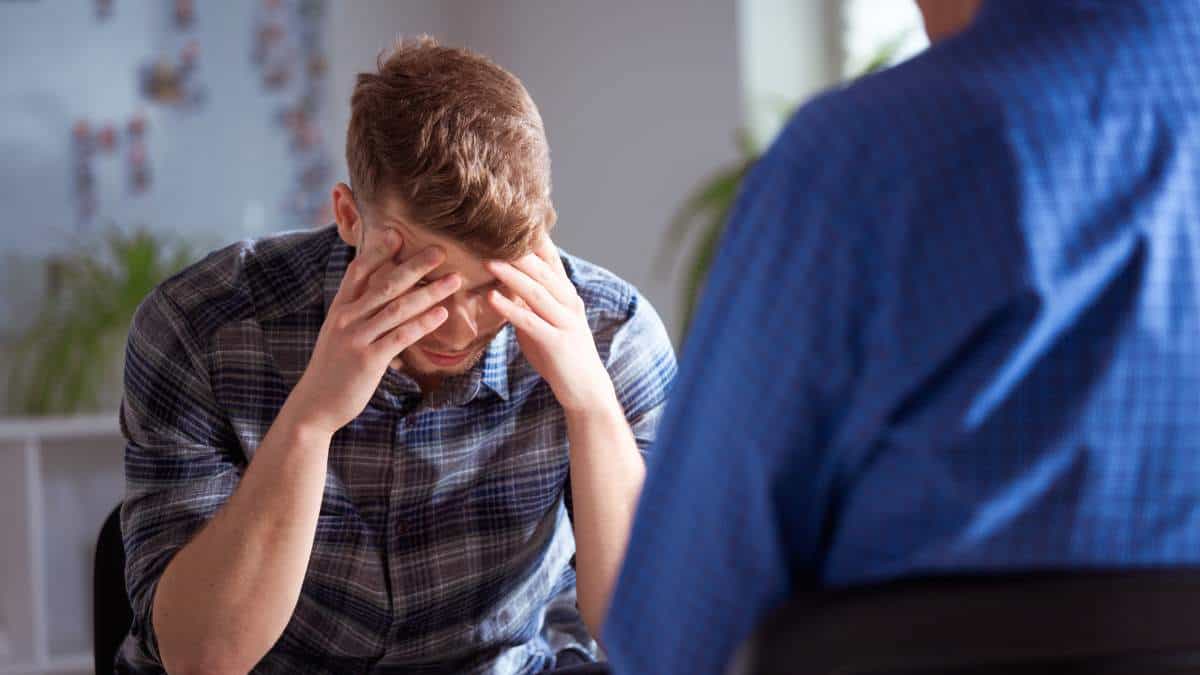 A man struggling with co-occurring disorders talking to a therapist during dual diagnosis treatment.