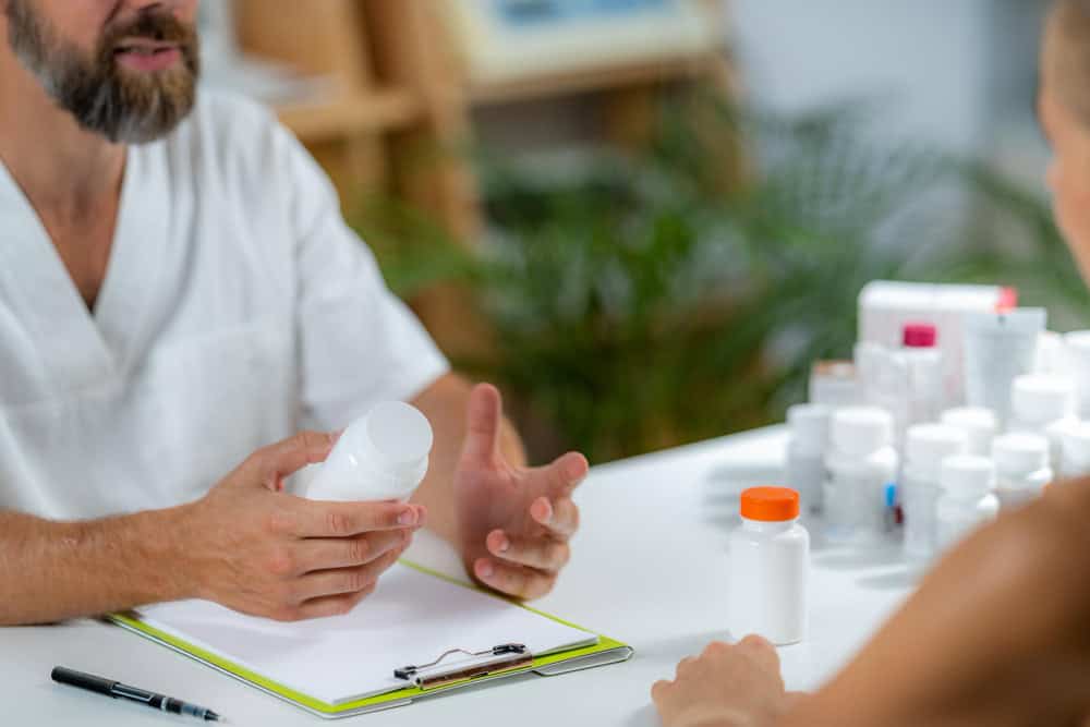 Quantum medicine doctor holding a supplement bottle recommending supplements to a client 