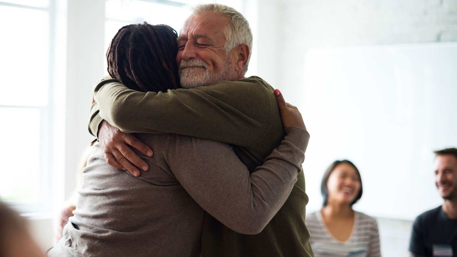 A man hugs his loved one during group therapy for those battling end-stage alcoholism.