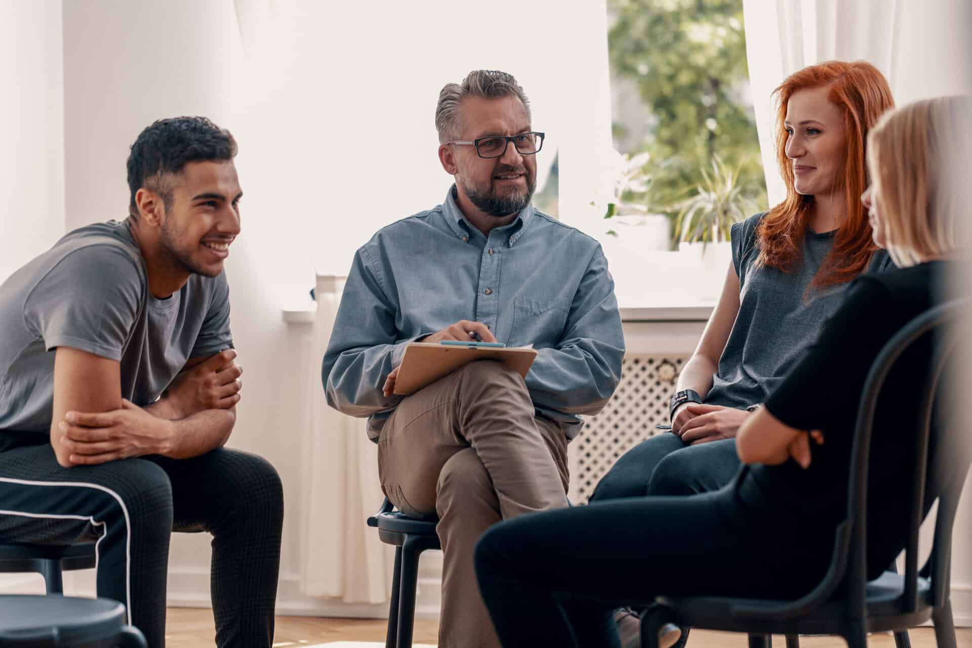 Smiling spanish man talking with friends during meeting for adults with therapist discussing Aetna Drug Rehab in New Jersey